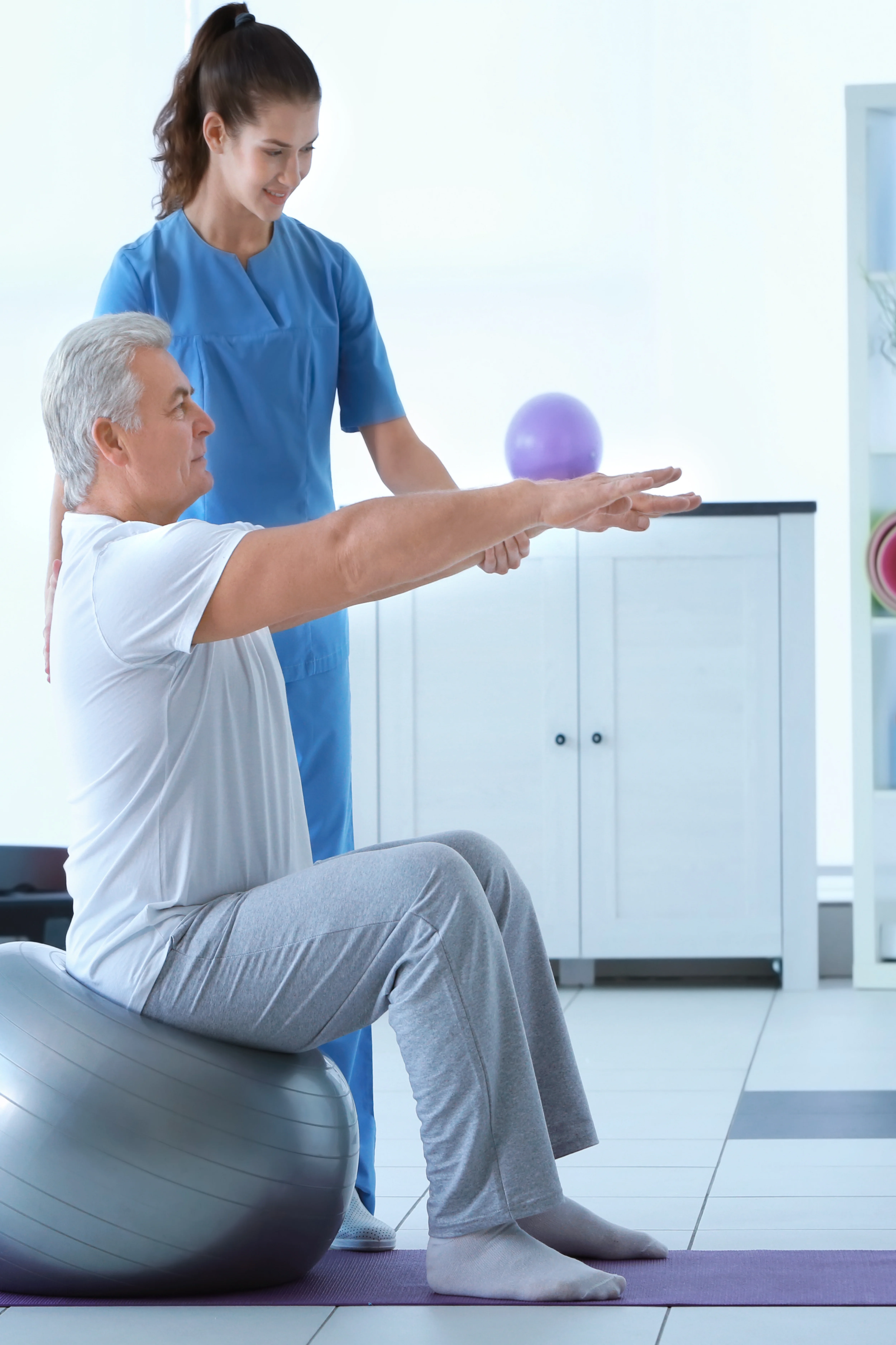 Profissional de fisioterapia auxilia utente com faixa elástica sobre marquesa.